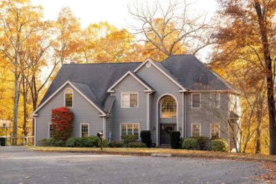 A large two-story house surrounded by autumn trees