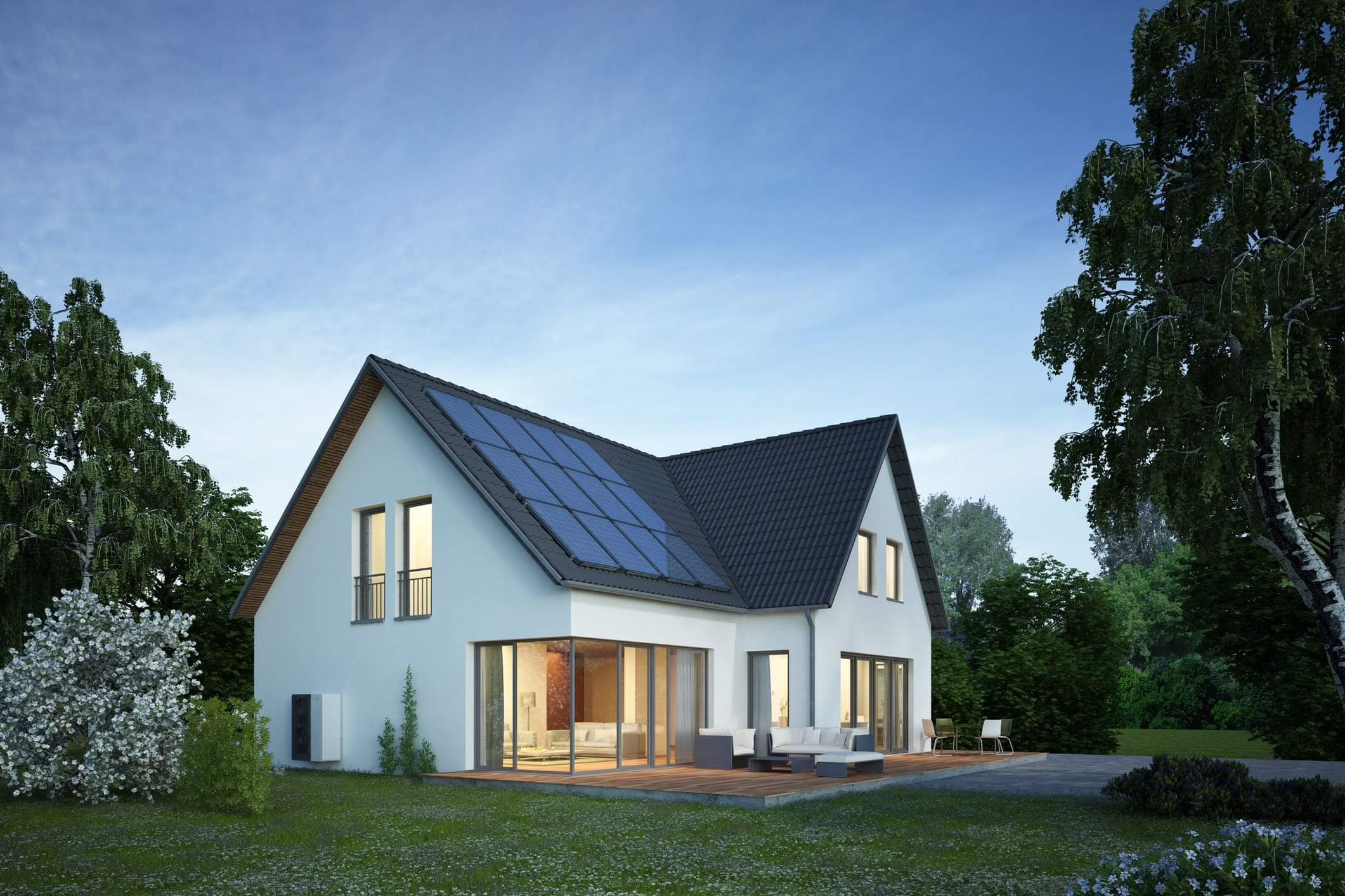 Modern white house with solar panels on the roof at dusk.