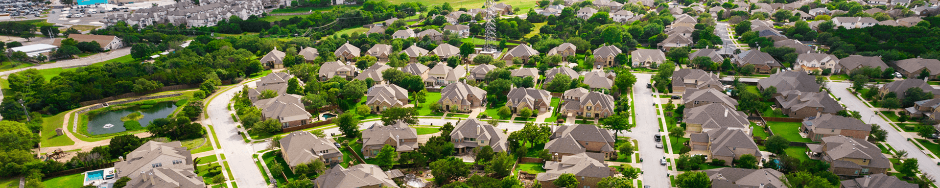 A suburban neighborhood with many similar houses surrounded by greenery.
