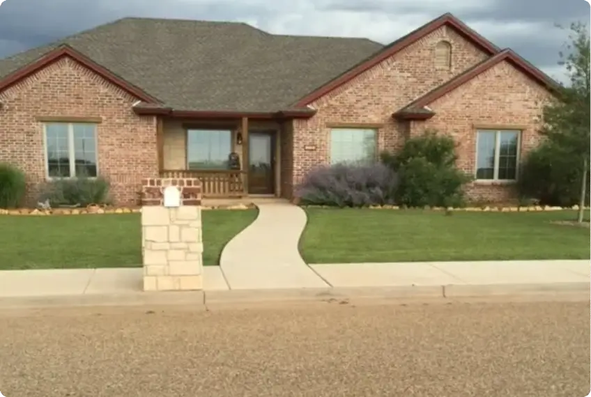 A brick house with a well-maintained front lawn and walkway.
