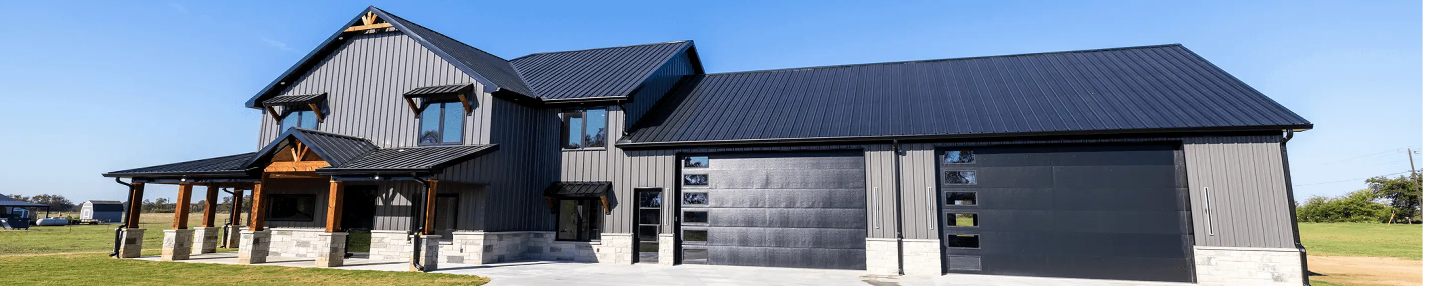 Gray farmhouse with dual black garage doors
